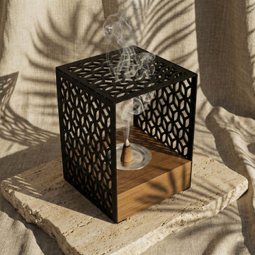 Wooden base mabkhara with a black Petal Lattice metal frame, close view with an incense cone burning