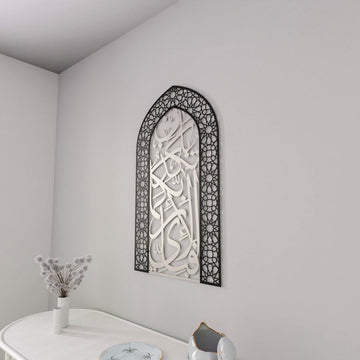 Black dome frame mihrab Surah Rahman verse 13 wall art with silver calligraphy above a white table