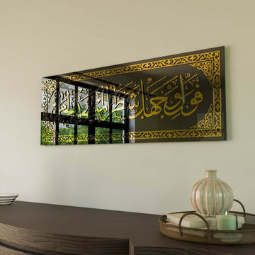 Gold Surah Baqarah 144 calligraphy on black glass at a sharp angle, window reflected in the glass