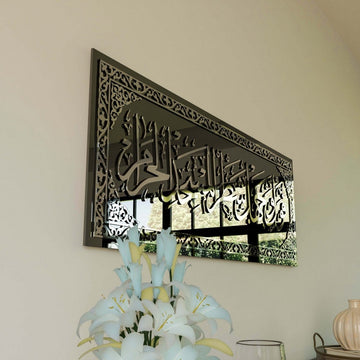 Silver Surah Baqarah 144 calligraphy on black glass seen from the side, with white lilies in front
