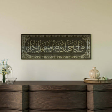 Silver Surah Baqarah 144 mihrab verse glass wall art with a glossy reflection above a sideboard