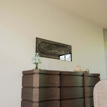 Silver Surah Baqarah 144 glass wall art above a chest of drawers, window reflected in the glass