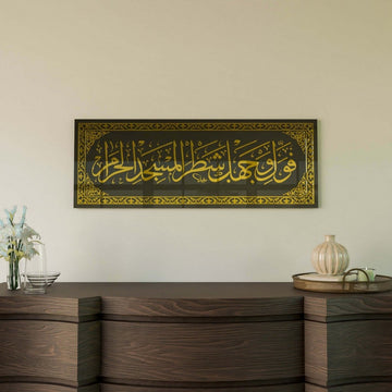 Gold Surah Baqarah 144 mihrab verse glass wall art, close view above a curved wooden sideboard