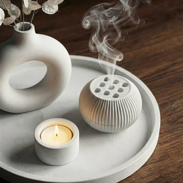 Decorative items including a candle, diffuser, and vase on a wooden surface.