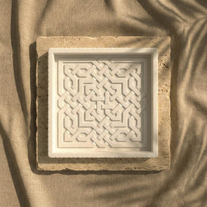 Top view of the Alhambra Nasrid Knotwork white stone relief tray on a travertine slab