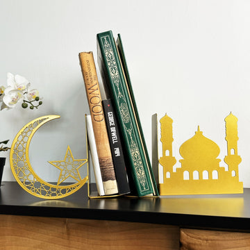 Goldene Metall-Buchstützen in Halbmond- und Moscheeform halten einen grünen Koran und andere Bücher auf einer schwarzen Konsole