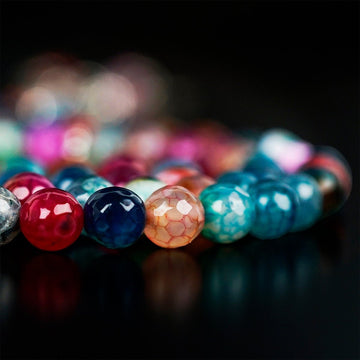 Low side view of faceted multi-colored agate prayer beads with blurred background on black