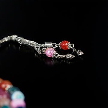 Silver tassel with leaf charms and red and pink agate beads on the multi-colored tasbeeh