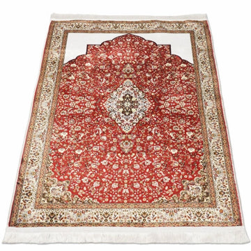 Tiefroter muslimischer Gebetsteppich mit Blumenmuster, flach ausgelegt und schräg auf Weiß gesehen