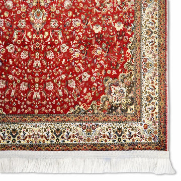 Ecke des tiefroten Gebetsteppichs mit cremefarbener Bordüre, Blumen und weißen Fransen