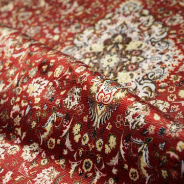 Nahaufnahme des tiefroten Gebetsteppichs mit Blumenmuster, gefaltet, mit Muster und weichem Flor