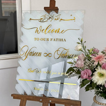 Gros plan du Bismillah doré, du texte de bienvenue et des noms sur le panneau Nikkah en verre blanc