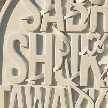 Gros plan sur les lettres Sabr et Shukr en relief avec traits de calligraphie arabe, en pierre moulée