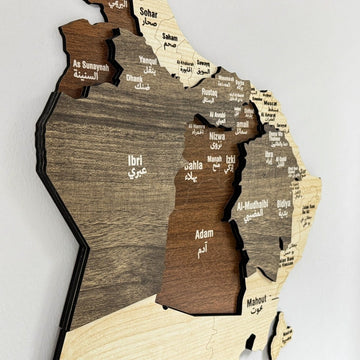 Gros plan des bords de bois en couches et des noms de régions en arabe et en anglais sur la carte d'Oman