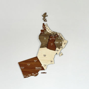Carte d'Oman 3D en bois en couches aux tons brun et crème, fixée sur un mur blanc