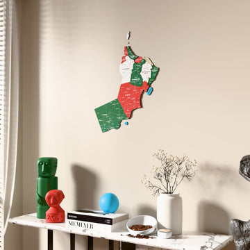Flag colored Oman wooden wall map beside a sheer curtain, angled view
