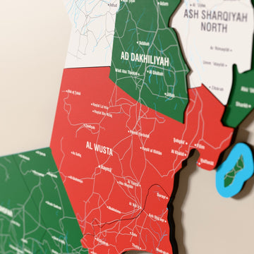 Close-up of the Flag colored Oman wooden wall map with layered regions and printed names