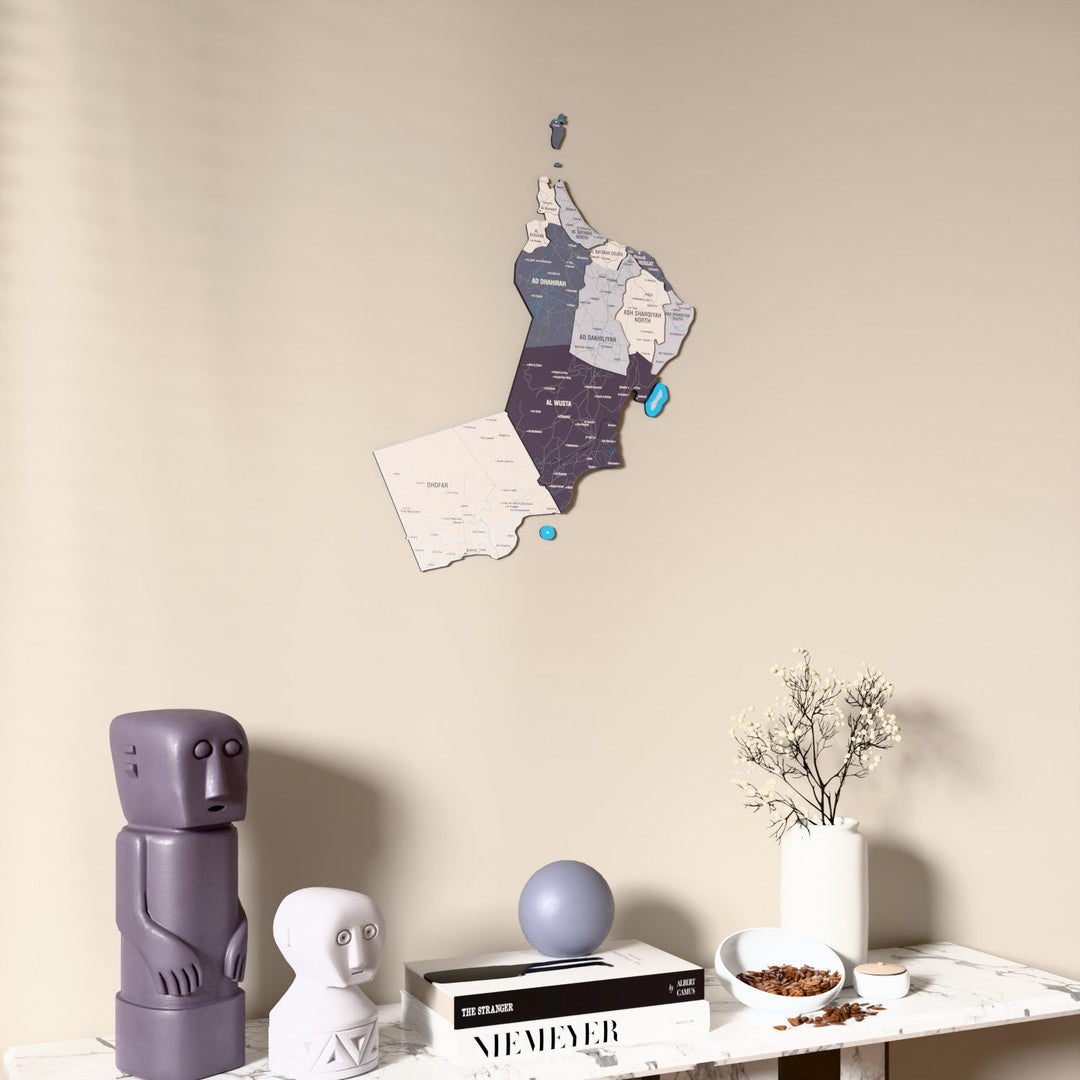 Nimbus Oman wooden wall map on a beige wall above a console with figurines