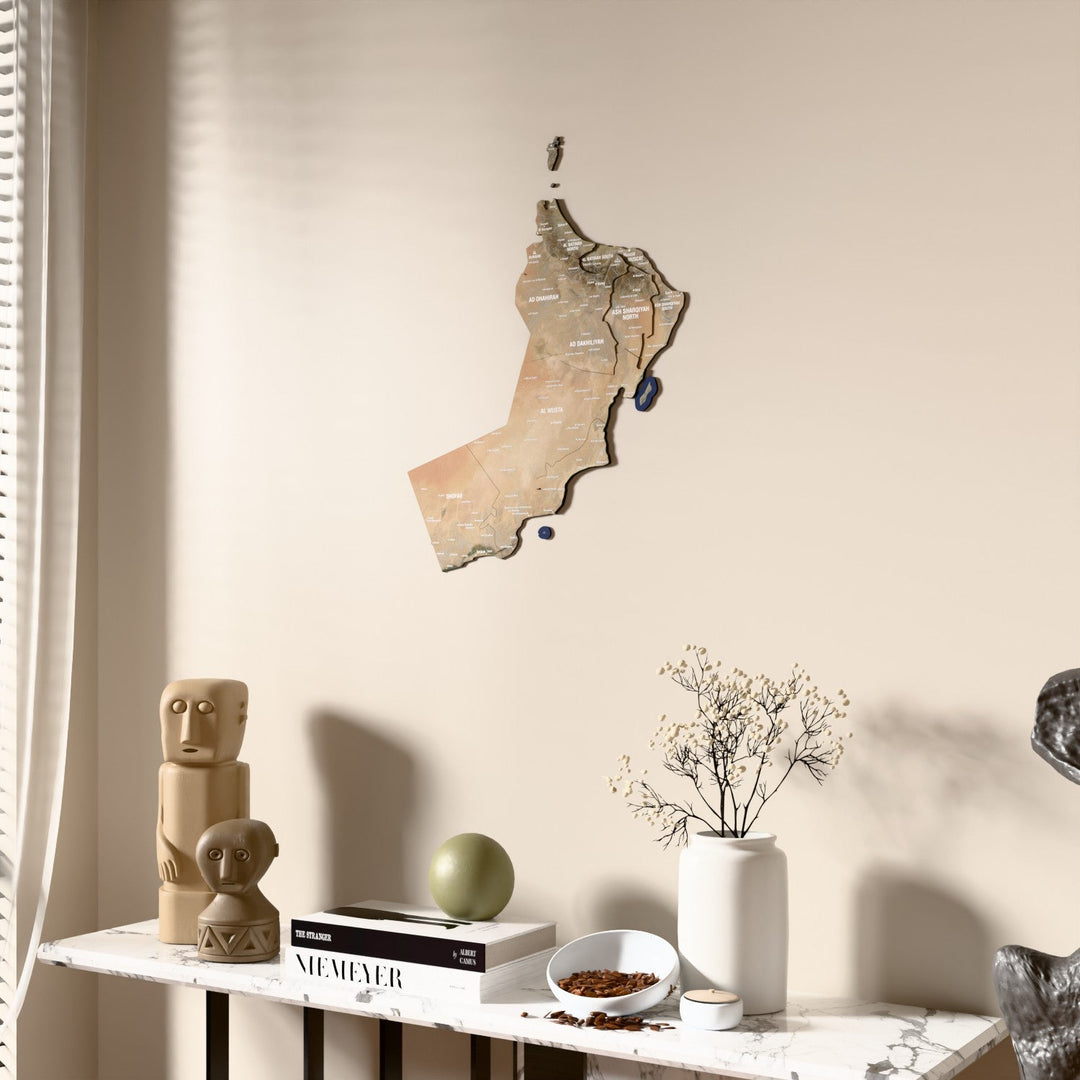 Satellite Oman wooden wall map beside a sheer curtain, angled view