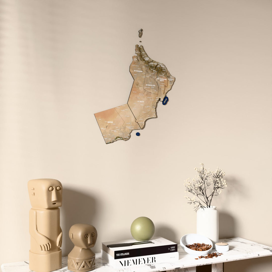Satellite Oman wooden wall map on a beige wall above a console with figurines