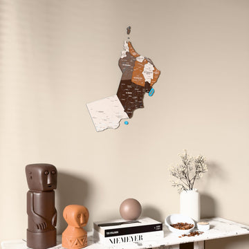 Soil Oman wooden wall map on a beige wall above a console with figurines