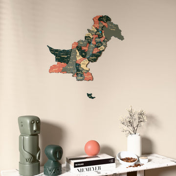 Sage Pakistan wooden wall map on a beige wall above a console with figurines