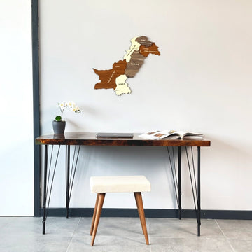 Carte murale du Pakistan en bois sur un mur blanc au-dessus d'un bureau et d'un tabouret rembourré