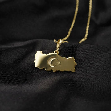 Gold Turkiye map pendant resting on black satin, crescent and star engraved