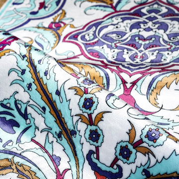 Close-up of the Pastel floral prayer rug with a folded edge showing aqua and magenta flowers