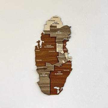 Carte murale du Qatar en bois aux tons de bois superposés et régions nommées sur un mur blanc
