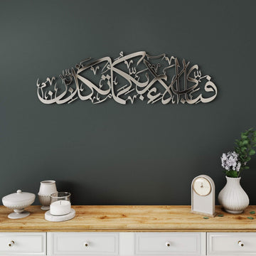 Surah Ar-Rahman verse 13 metal wall art in Shiny Silver on a dark gray wall above a console