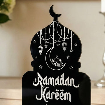 Close-up of black acrylic mosque decor with crisp UV white printed Ramadan Kareem Arabic and English calligraphy.