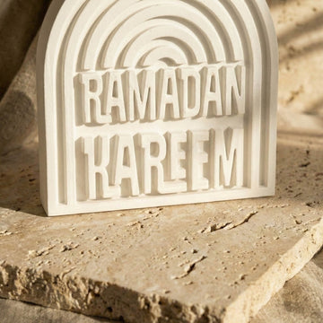 Close-up of the Ramadan Kareem raised lettering and fluted arch on a stone slab