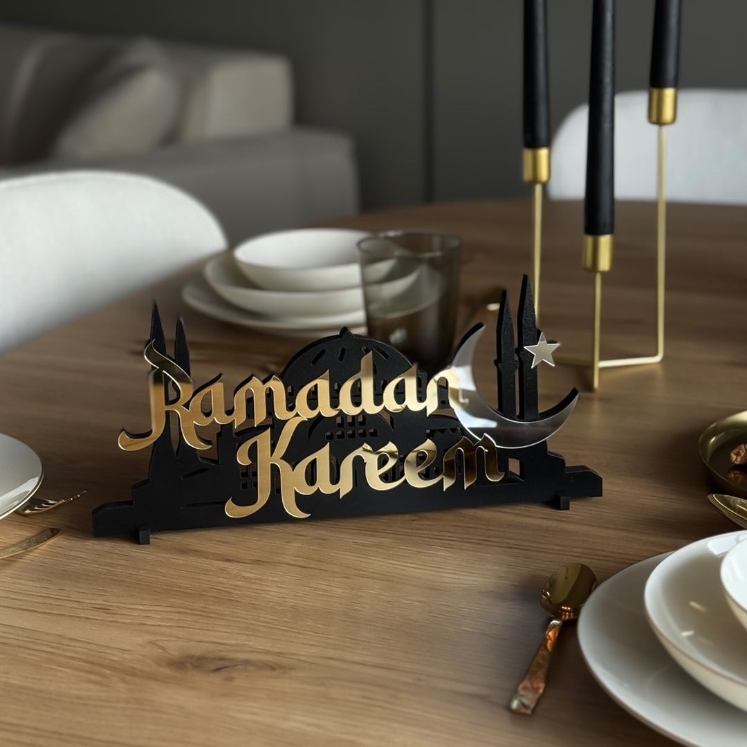 Decorative sign with 'Ramadan Kareem' on a dining table with plates and glasses.
