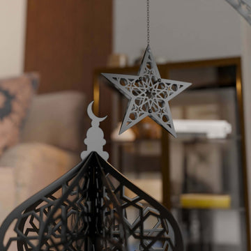 Close-up of the black lantern dome with a hanging silver-gray star and crescent finial