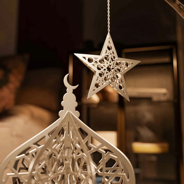 Close-up of the white lantern dome with a hanging silver star and crescent finial