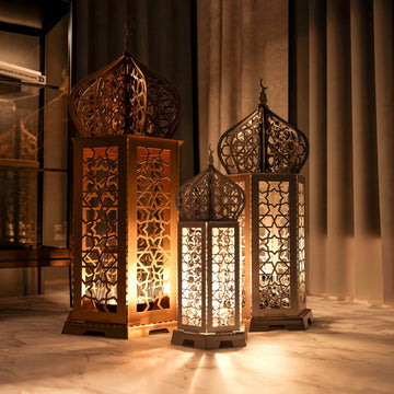Gold, white and black Ramadan lanterns of different heights glowing in a dim room