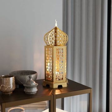 Gold Ramadan lantern metal decor lit from inside on a dark side table