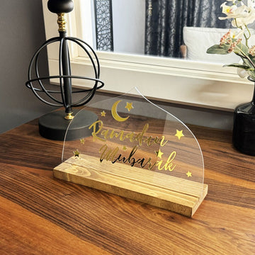 ديكور «رمضان مبارك» شفاف صغير على مكتب خشبي مع مصباح كروي خلفه