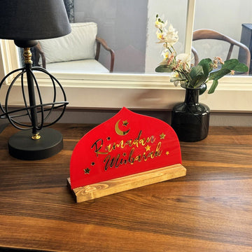 ديكور «رمضان مبارك» أحمر صغير على مكتب بجانب مصباح أسود ومزهرية داكنة