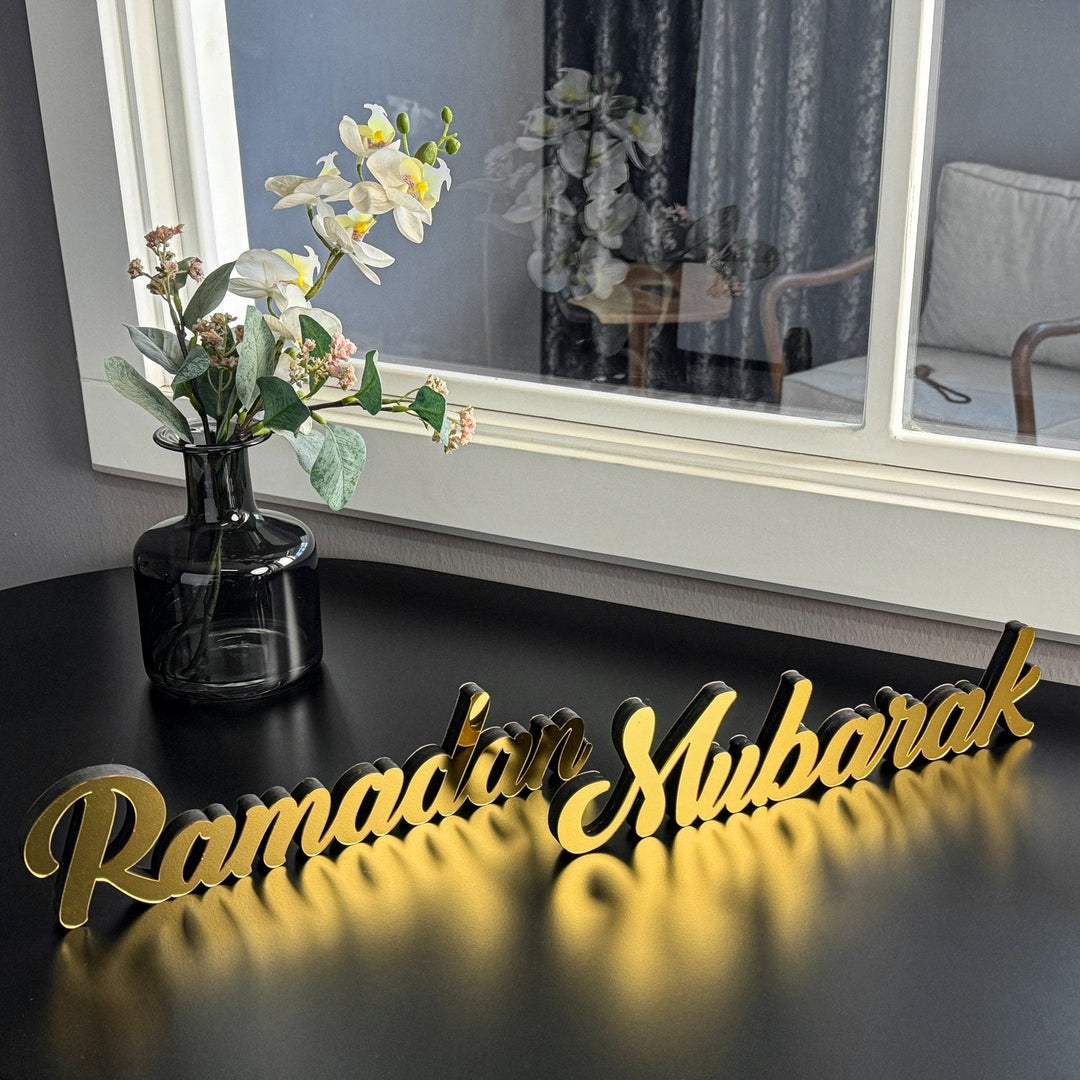 Décoration de table dorée Ramadan Moubarak en écriture latine, vue en angle depuis le haut gauche avec un vase de fleurs