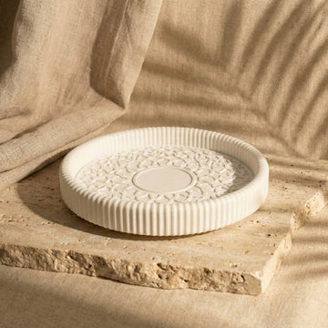 Decorative ceramic plate with intricate design on a textured stone surface