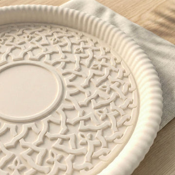 Decorative white ceramic plate with intricate patterns on a wooden surface