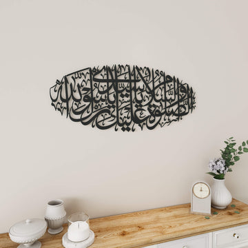 Black Salawat on Rasulullah metal wall art above a wooden shelf with a clock and vase