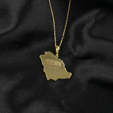 Gold Saudi Arabia map pendant necklace hanging on a fine chain over black fabric