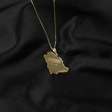 Gold Saudi Arabia map necklace on a long thin chain against black fabric