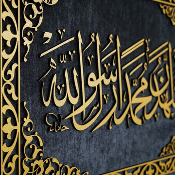 Close-up of raised gold Second Kalima calligraphy on dark velvet with the frame ornament at the left