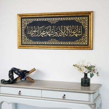 Second Kalima framed wall art above a white console, closer view with a Quran stand and vase