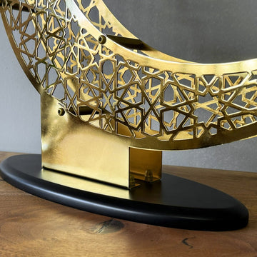Low close-up of the metal stand joining the Shiny Gold crescent to its black oval base