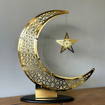 Large Shiny Gold crescent and star decor on a wooden sideboard with a black oval base